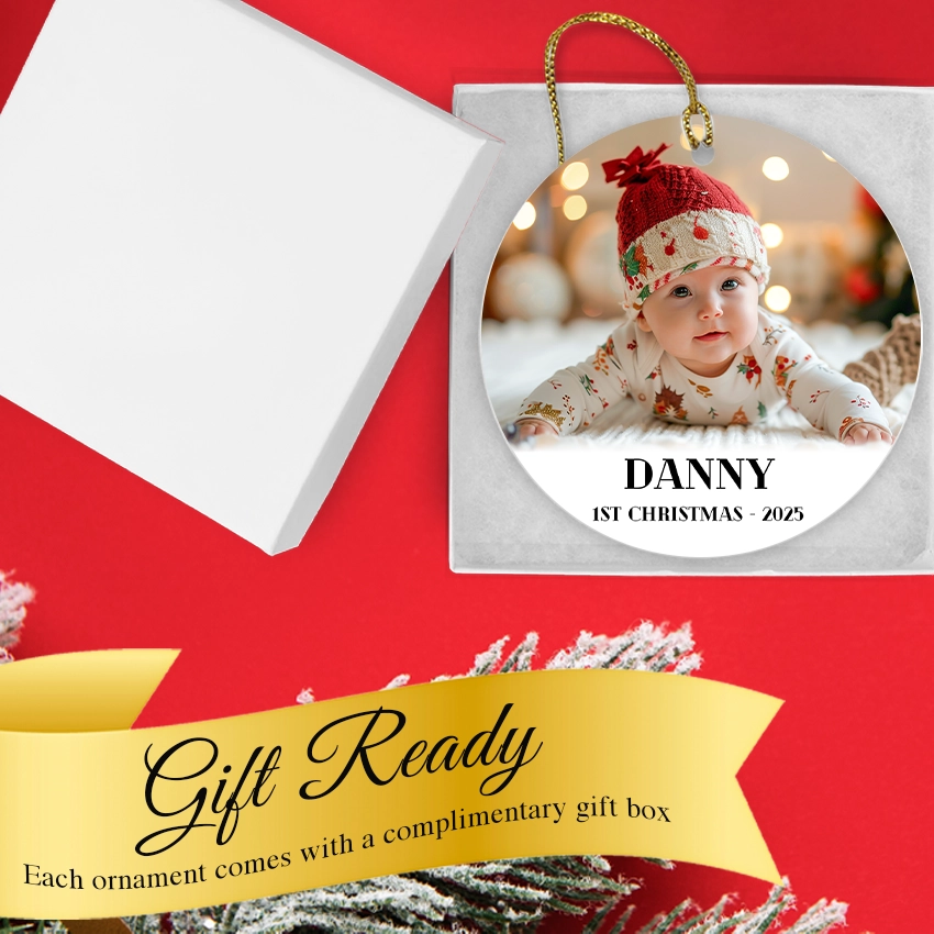 A custom baby photo Christmas ornament shown inside its elegant white gift box with a gold ribbon.