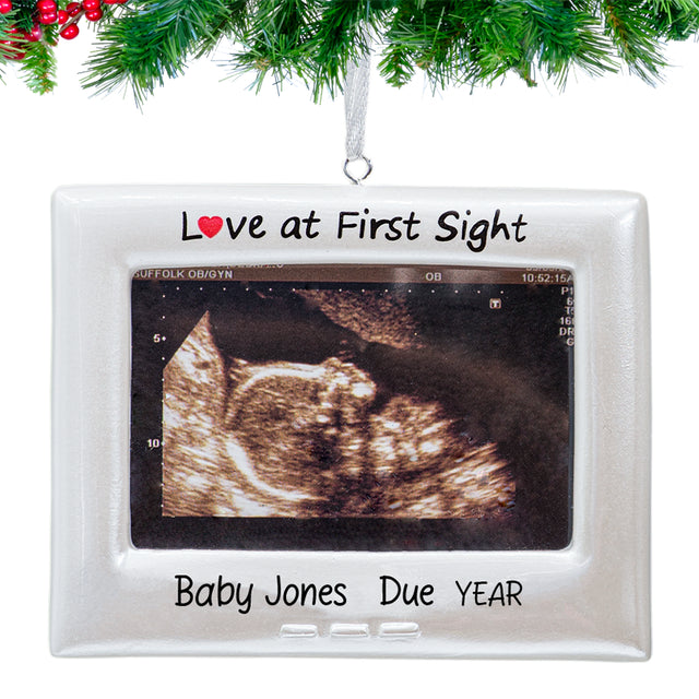 Ornament featuring a sonogram photo, personalized hanging on a festive Christmas tree branch.