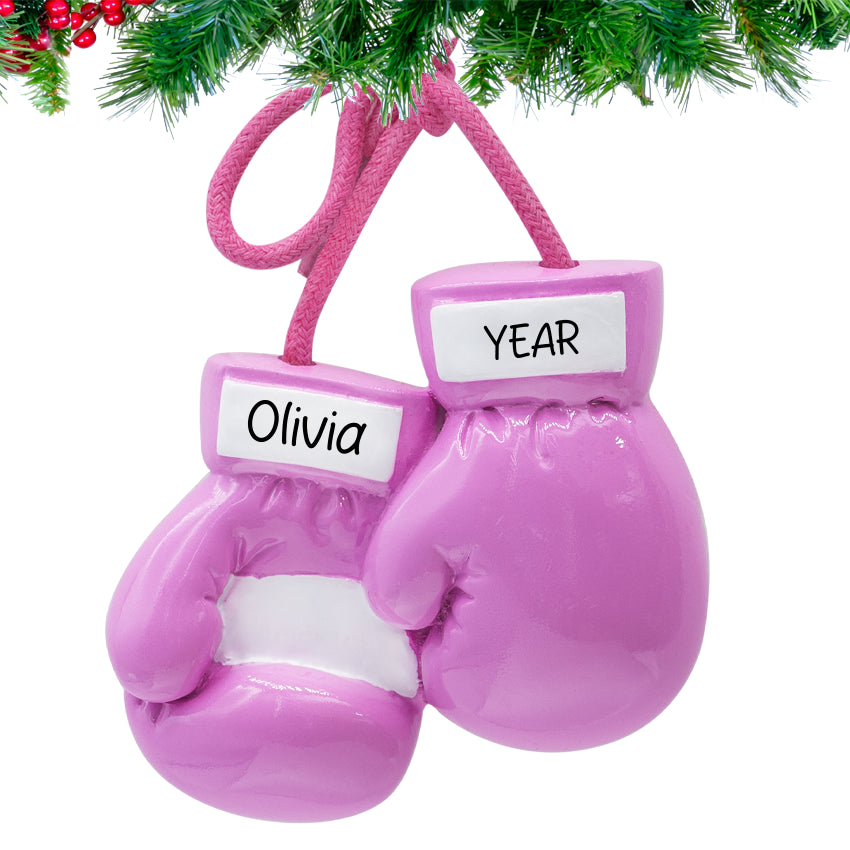 Pink boxing gloves ornament with 'Olivia' and 'YEAR' labels, hanging from a Christmas tree.