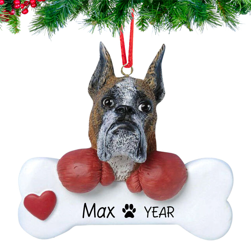 Smiling Boxer Dog holding a bone nameplate, personalized with dog’s name and 2025, hanging on a festive Christmas tree branch.