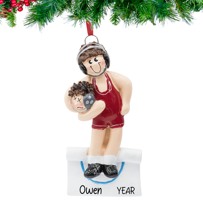 Christmas ornament of a person in a red outfit holding a child, with 'Owen' and 'YEAR' on a tag, hanging from a tree.