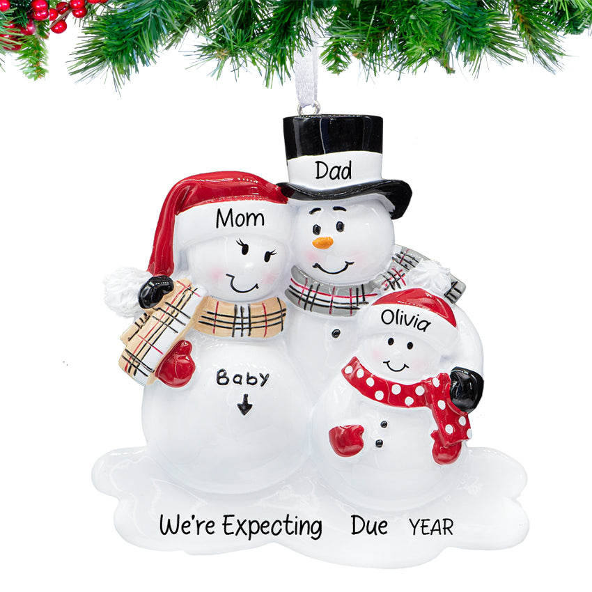 Snowman parents holding a snow-baby, ornament personalized with two names, “Baby on the Way,” and 2025, hanging on a festive tree branch.