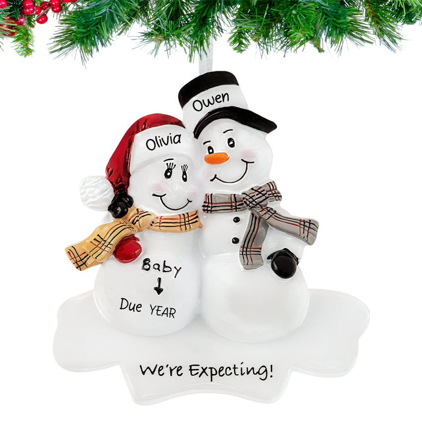 Expecting snowman couple ornament personalized with parent names, baby nickname, and 2025 hanging on a Christmas tree branch.