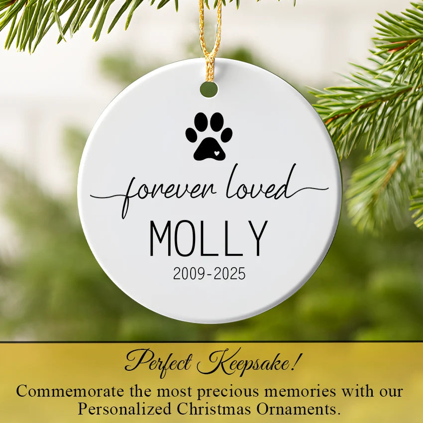 Personalized Christmas ornament with paw print and text 'forever loved  against a green foliage background.