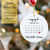 Engagement date ornament hanging on a Christmas tree branch with warm lights