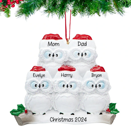 Smiling owl parents with two owlets on a snowy branch, ornament personalized with four names and 2025, hanging on a festive Christmas tree.