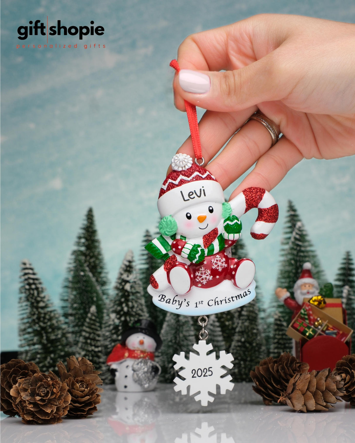 Personalized Christmas ornament with 'Baby's 1st Christmas 2025' text, held by a hand against a festive background.
