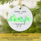 Engagement ornament hanging on a Christmas tree branch near pine needles